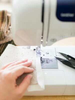 A close-up image showcasing a sewing machine actively stitching fabric with scissors nearby.