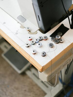 A detailed view of sewing machine bobbins and threads on a work surface in a crafting area.