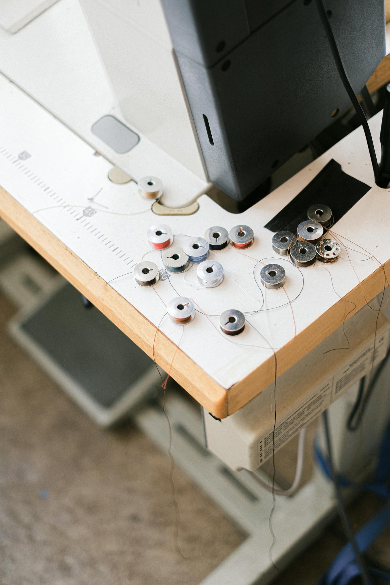 A detailed view of sewing machine bobbins and threads on a work surface in a crafting area.