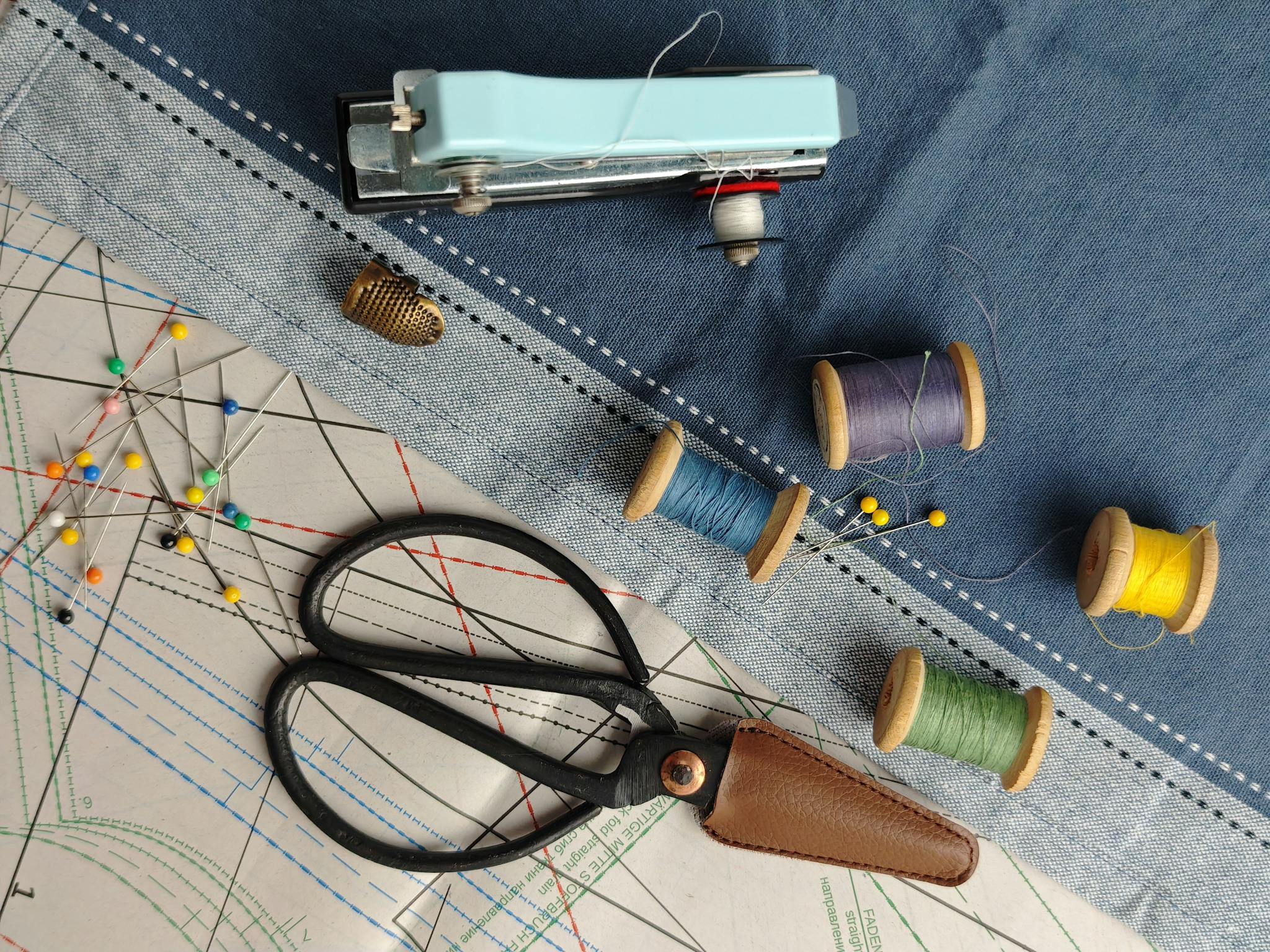 A flat lay of sewing supplies including threads, scissors, and a pattern on fabric.