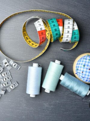 Photo by Jacob Moseholt A vibrant arrangement of sewing tools including thread, tape measure, and scissors on a dark background.