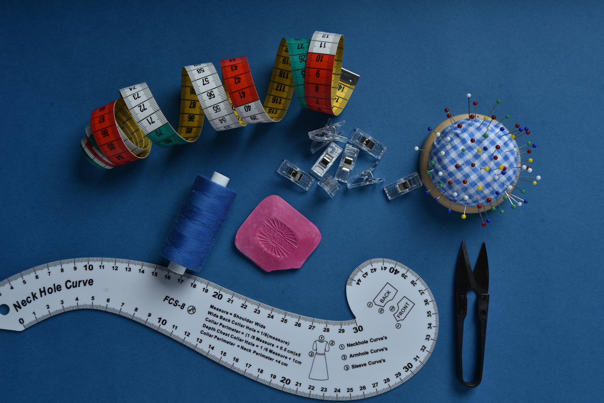 Sewing kit with colorful tools on a blue background, perfect for DIY and crafts.