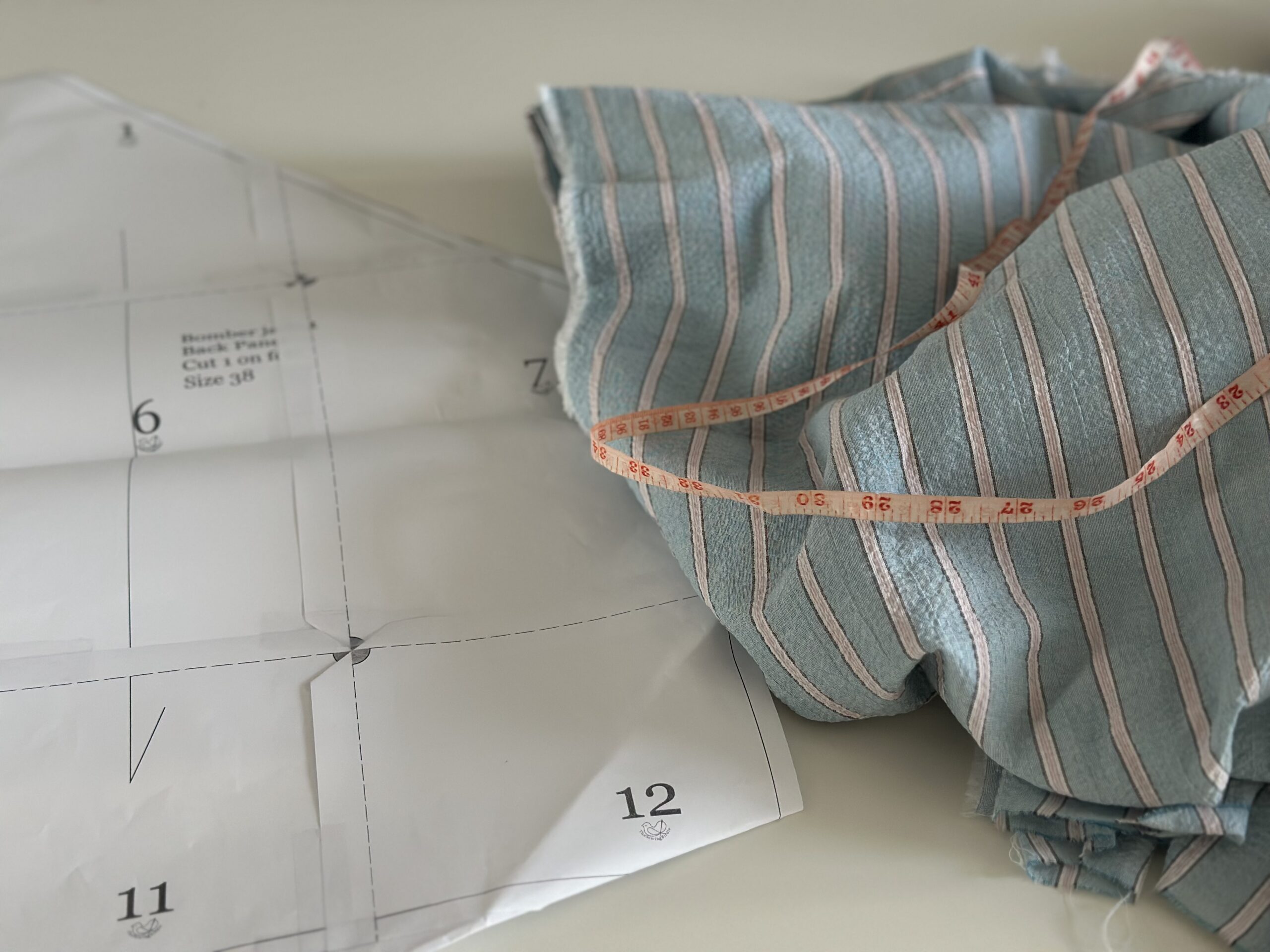 Taped PDF pattern sheet with a pattern piece pinned onto striped fabric