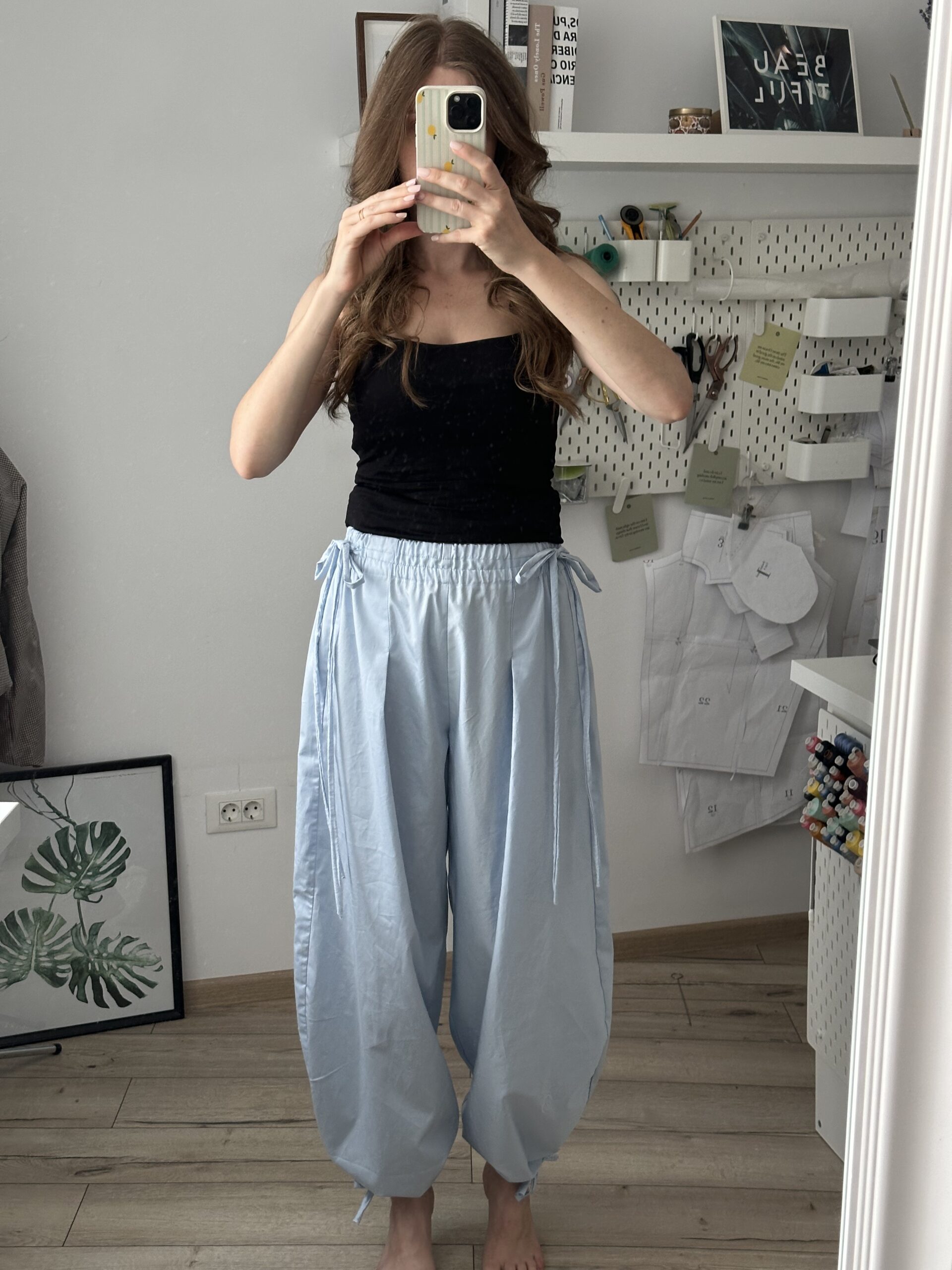 Wide-leg trousers styled with a fitted black tank top, full-length mirror outfit