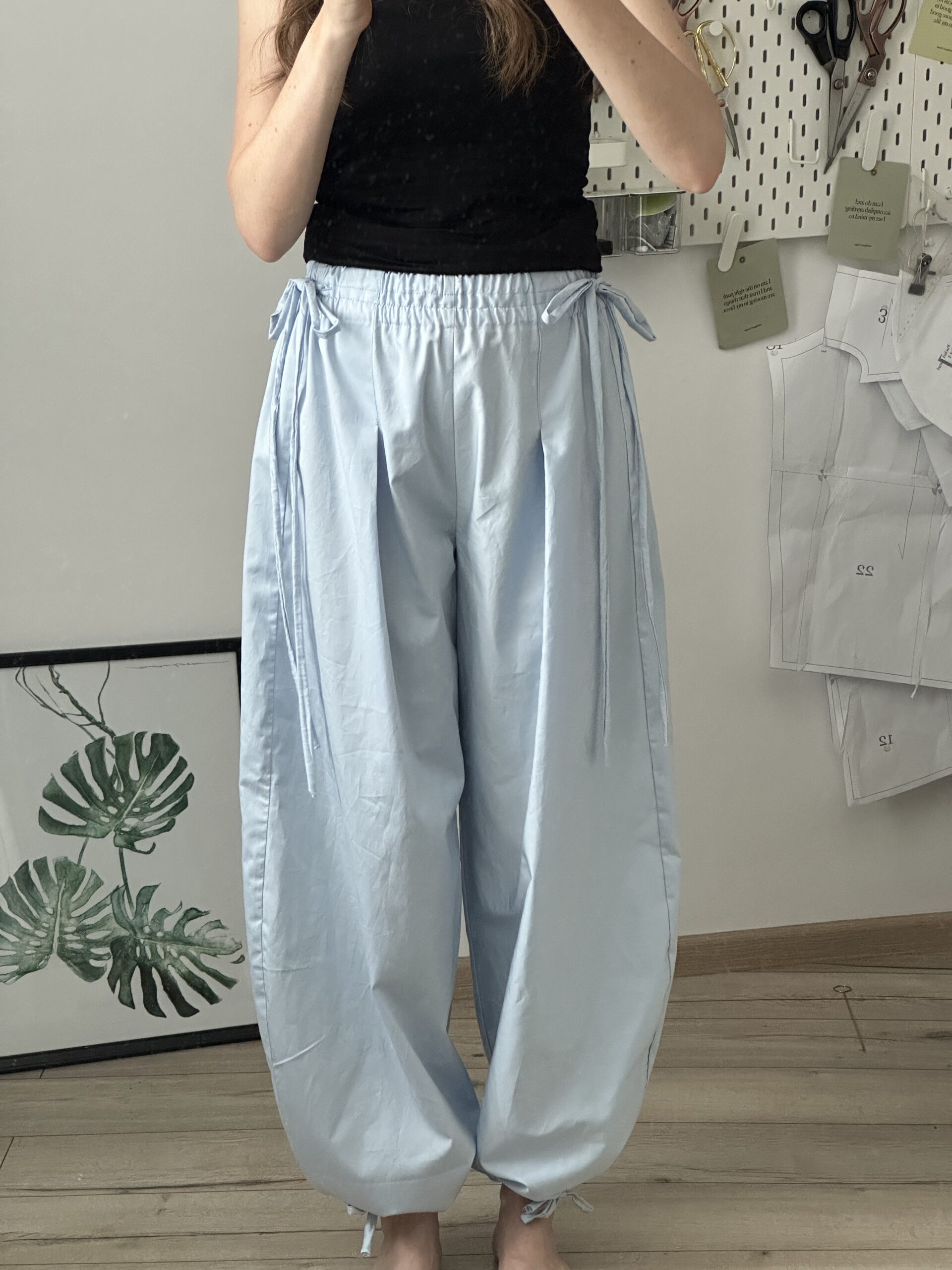 Fitted black top tucked into high-waisted light wide-leg trousers