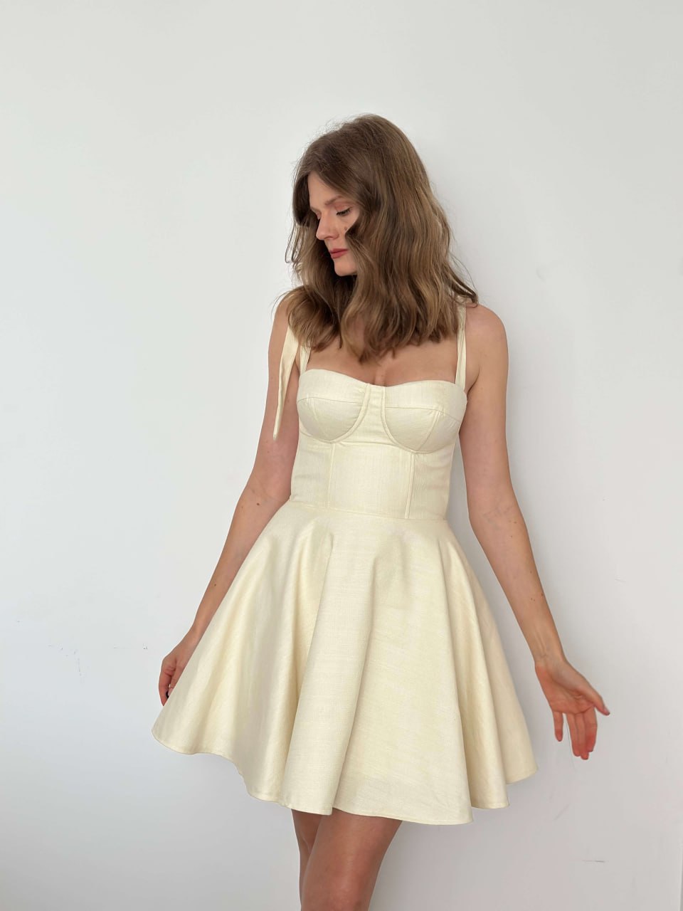Cream bustier mini dress with corset-style bodice and flared skirt, side view