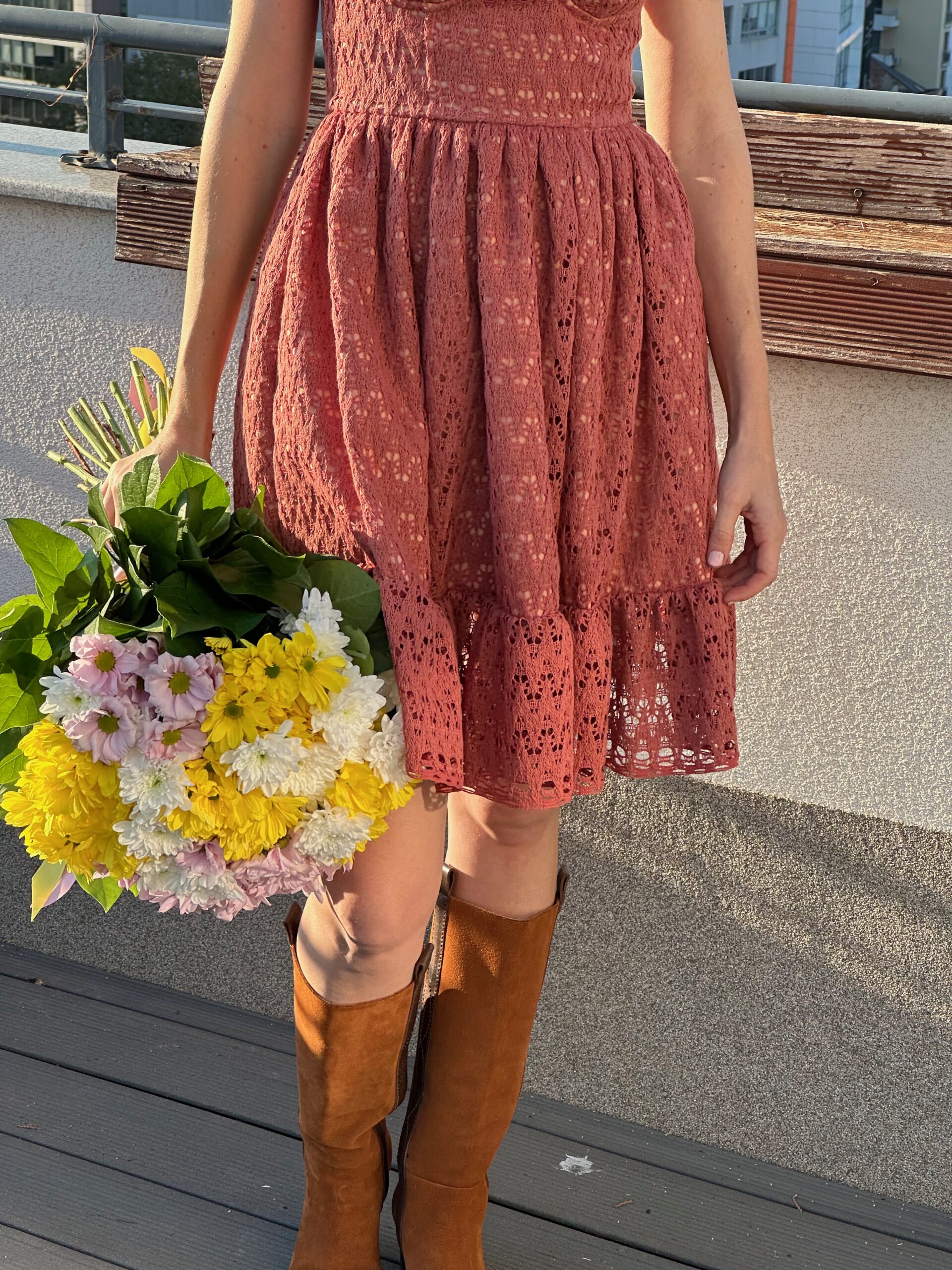 Bustier Dress in red floral print worn full length, holding a bunch of flowers