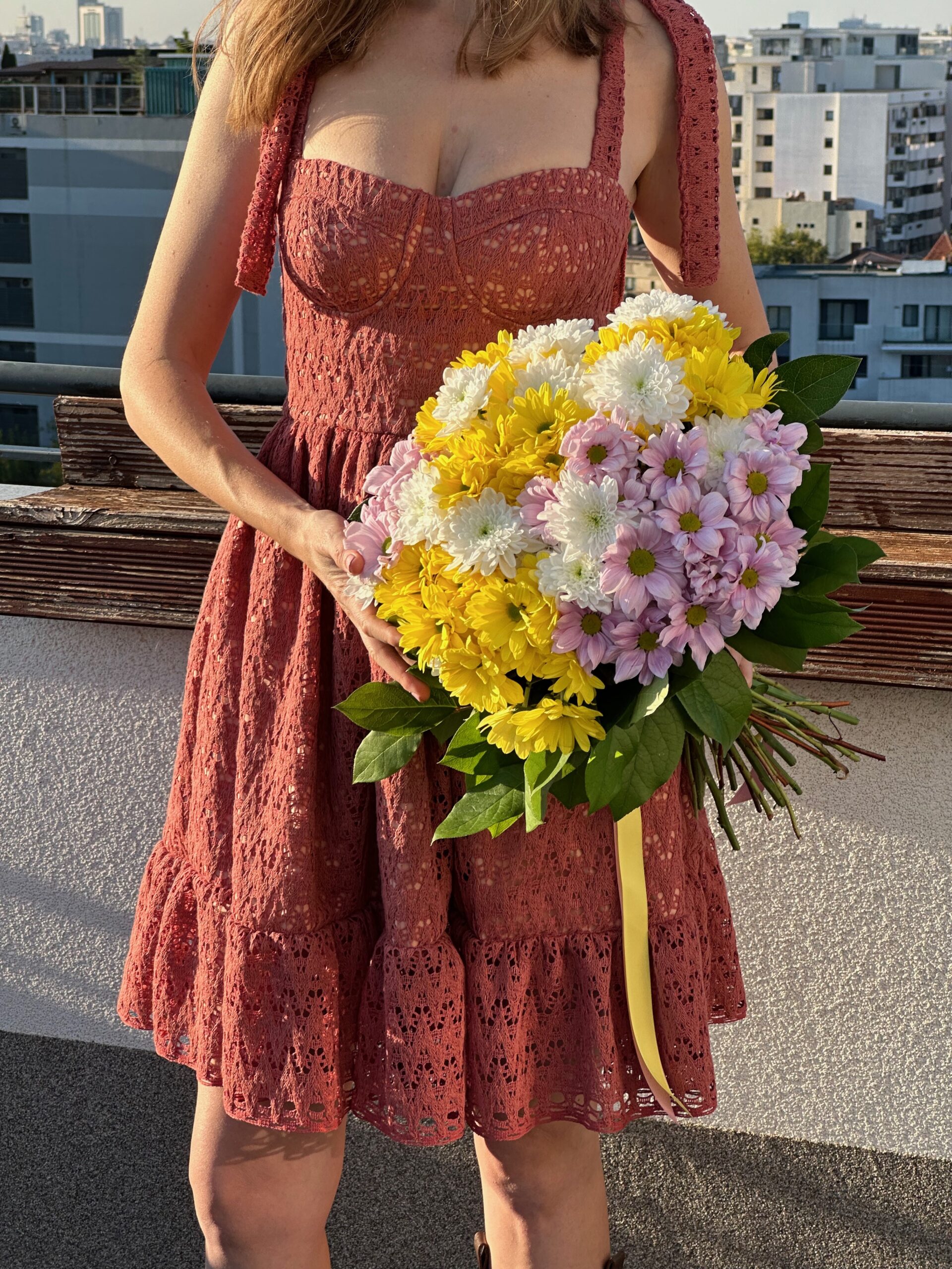 Bustier Dress in red floral print, three-quarter view, holding flowers