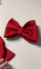 The finished fabric bow with loops, tails and centre knot on a white surface