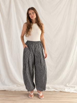 Jasmine balloon pants sewn in a black and white gingham check, worn with a white tank top, hands in the pockets