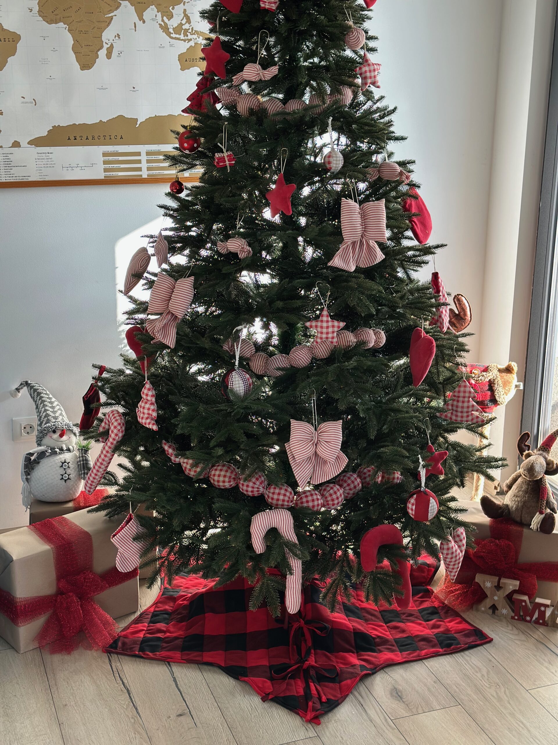 Quilted Christmas tree skirt in red and black buffalo check, tied with bows around the base of a decorated Christmas tree