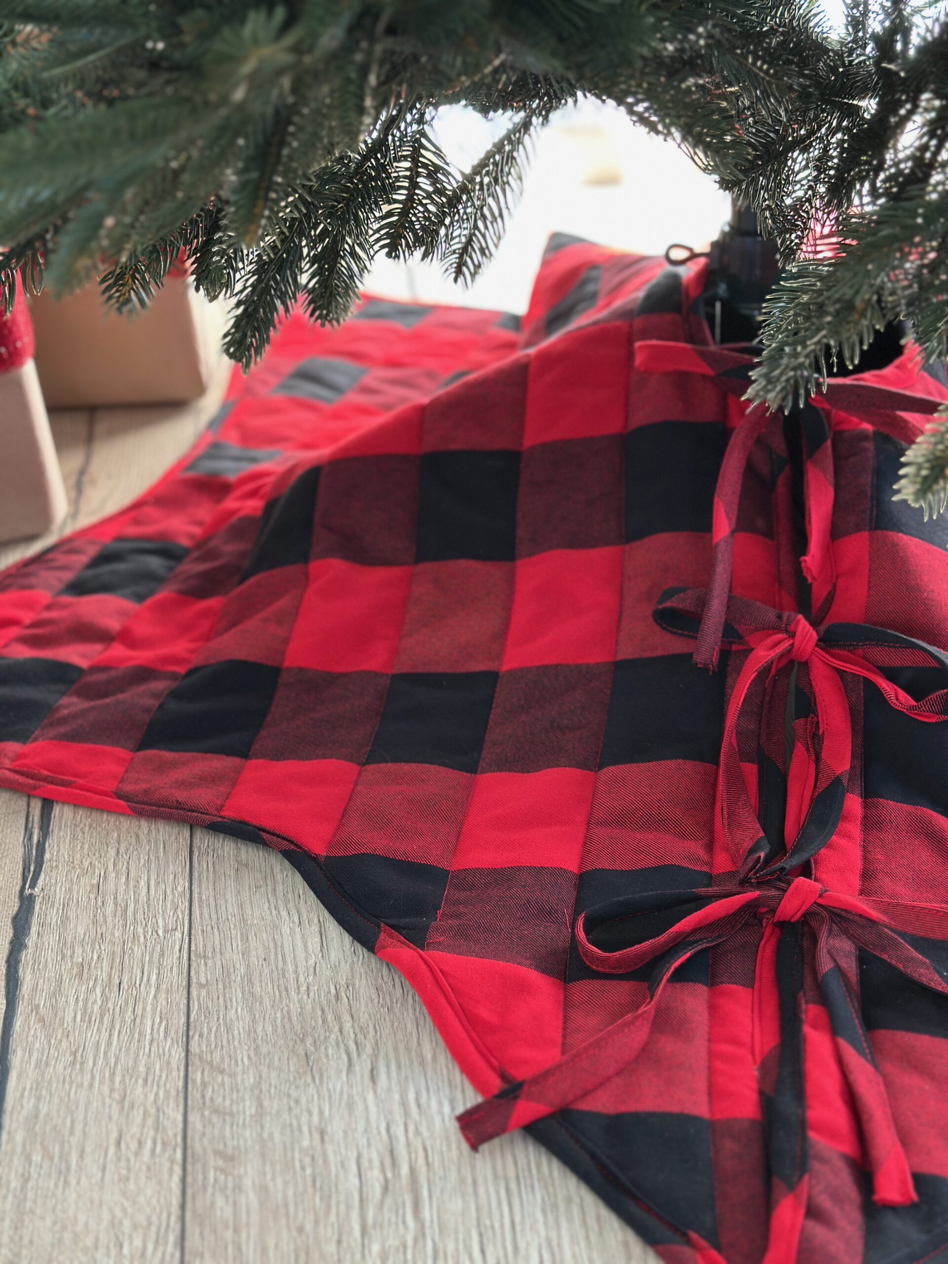 Quilted buffalo check tree skirt draped around the base of a Christmas tree, showing the folds