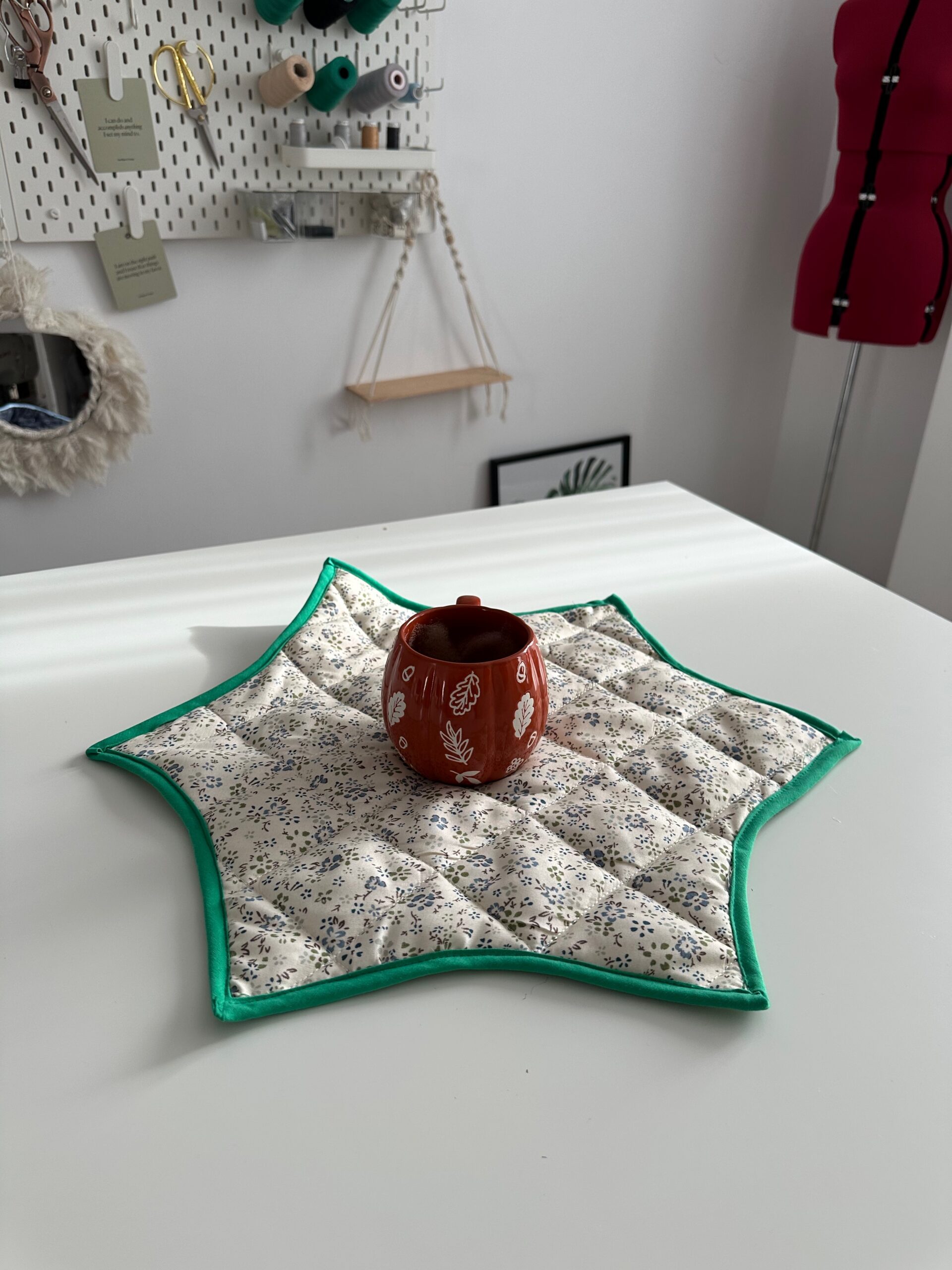 Quilted star-shaped table topper on a white table with a red candle holder